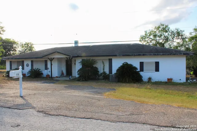 a front view of a house with a garden and a tree