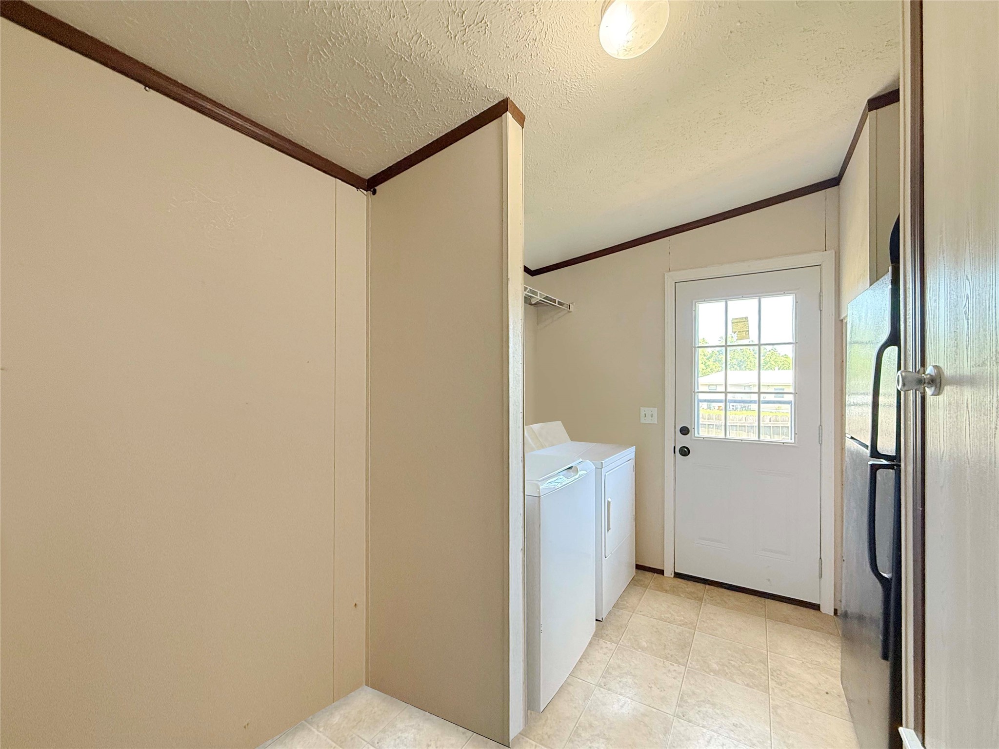 845 Caldwell Street Lexington, TX 78947 - Photo 18 of 39 Laundry area featuring ornamental molding, washing machine and clothes dryer, and a textured ceiling