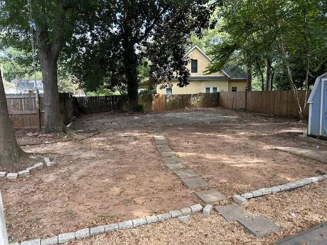 a view of a white house next to a yard with large trees