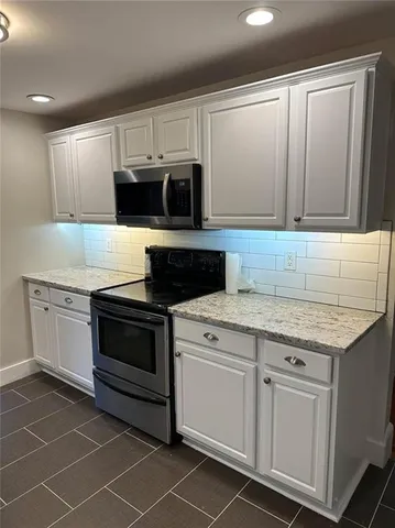 a kitchen with granite countertop white cabinets stainless steel appliances and a sink