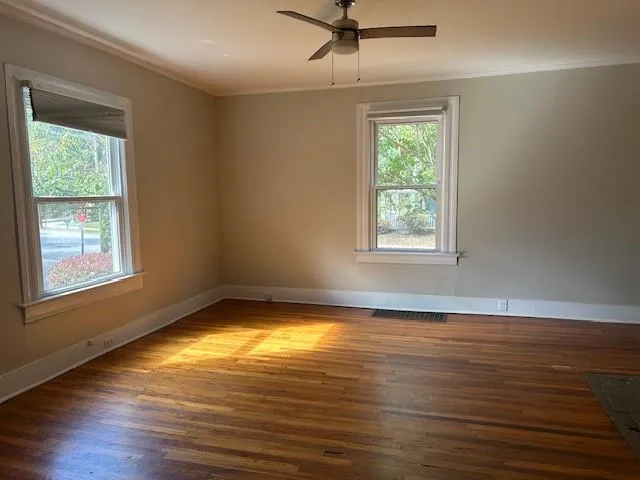 a view of an empty room with wooden floor and a window