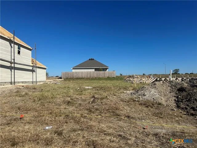 a view of a dry yard with wooden fence