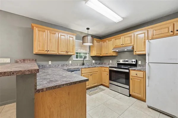 a kitchen with stainless steel appliances granite countertop a stove sink refrigerator and cabinets
