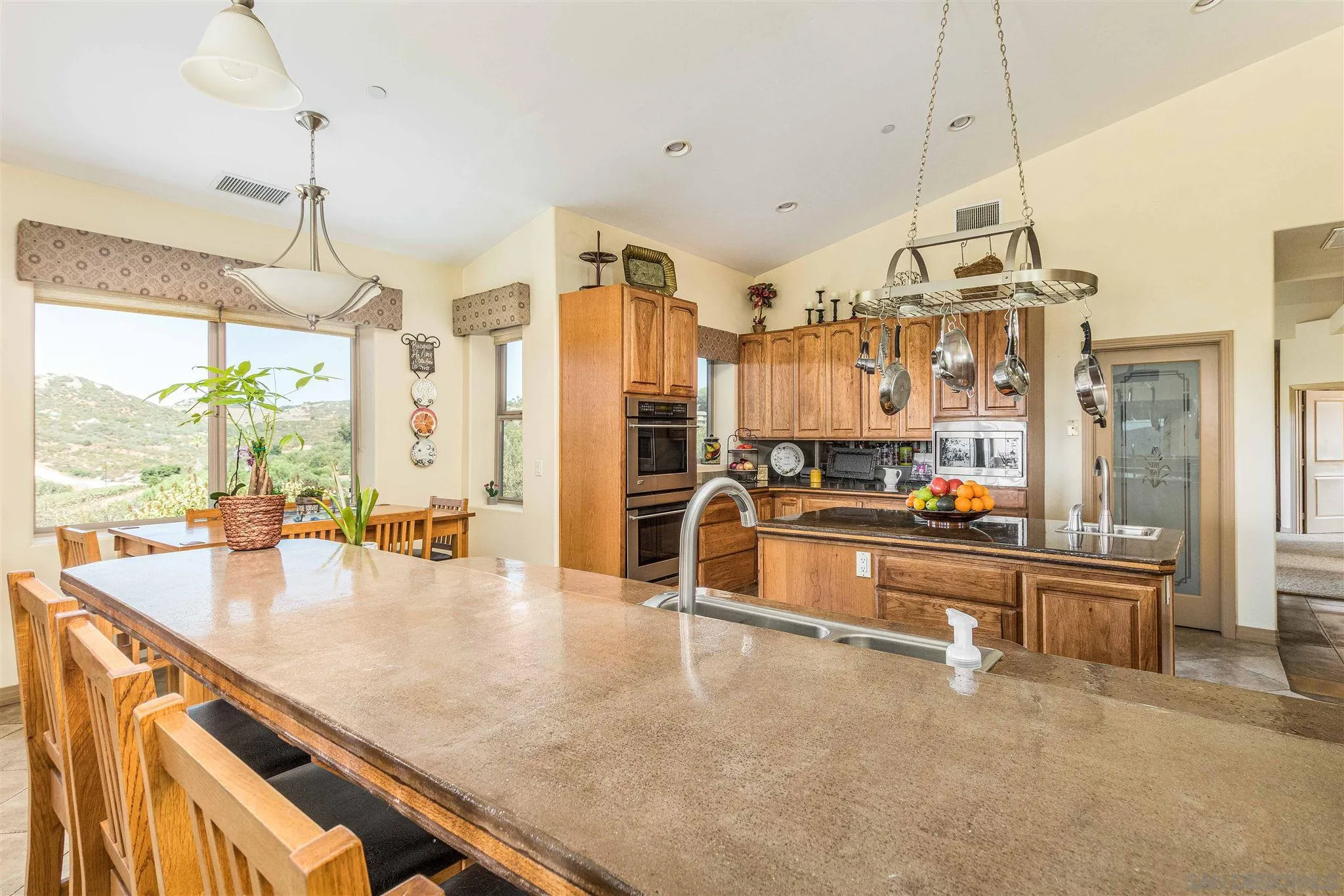 29482 Paso Robles Road Valley Center, CA 92082 - Photo 13 of 37 a large kitchen with kitchen island a stove a sink a counter space and dining table