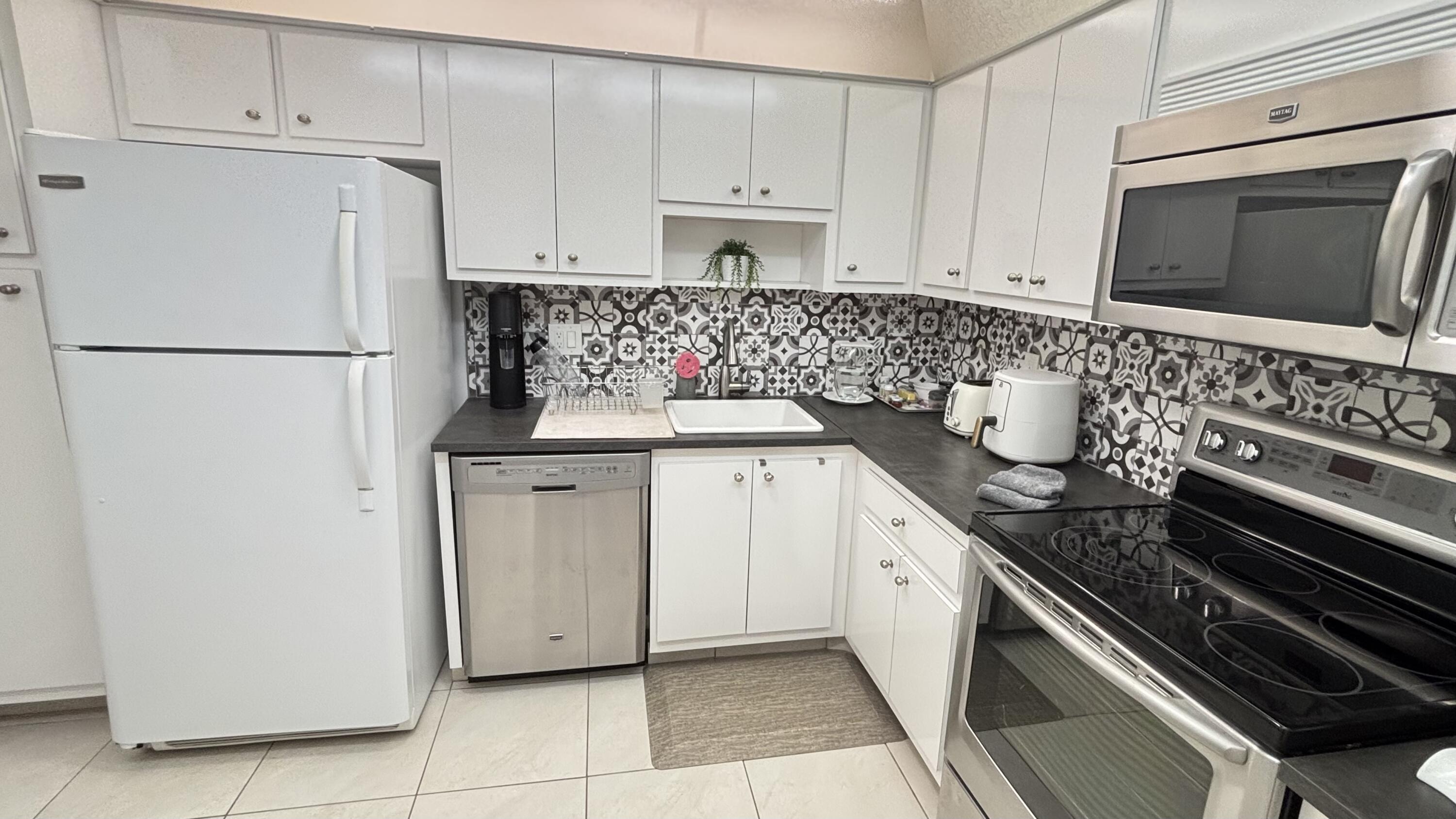 605 Oaks Drive, Unit 503 Pompano Beach, FL 33069 - Photo 3 of 15 a kitchen with granite countertop white cabinets and refrigerator