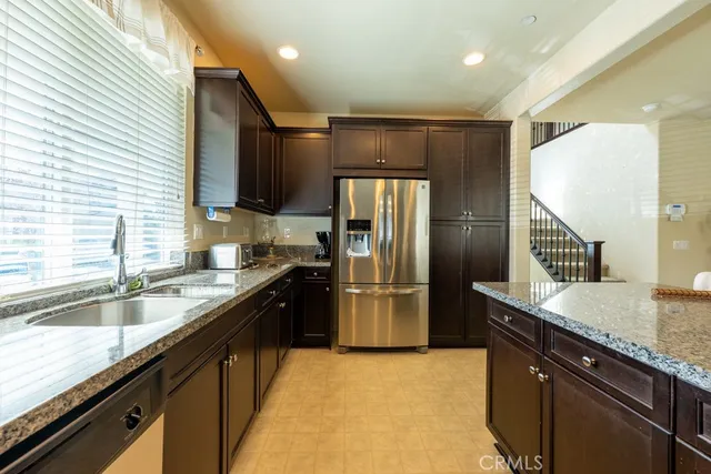 a large kitchen with granite countertop lots of counter top space a sink and dishwasher a stove top oven with wooden floor