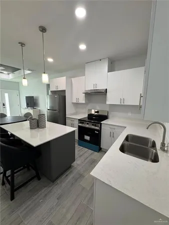 a kitchen with kitchen island a sink a stove a counter space and cabinets