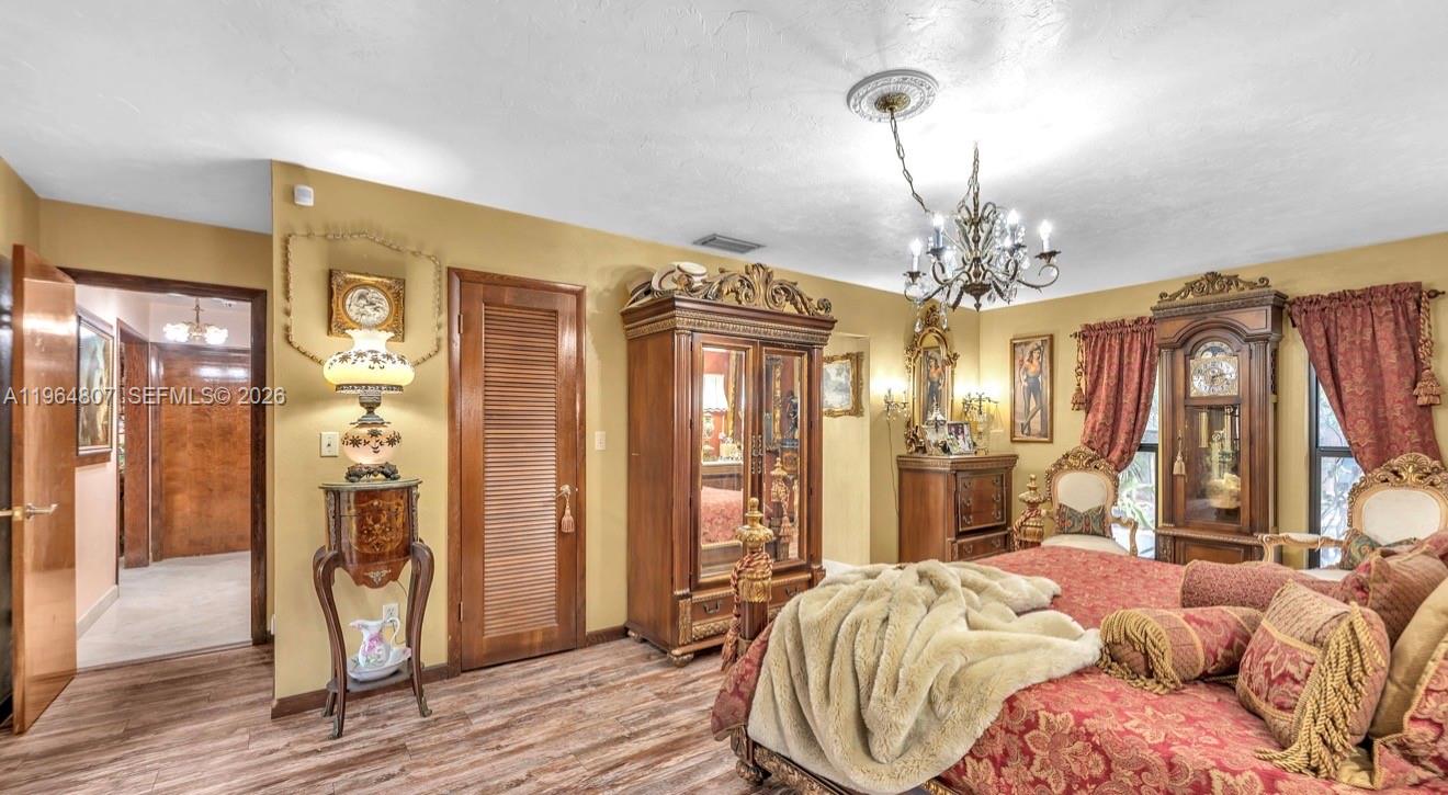 15425 Southwest 268th Street Homestead, FL 33032 - Photo 19 of 62 a spacious bedroom with a bed table and a chandelier