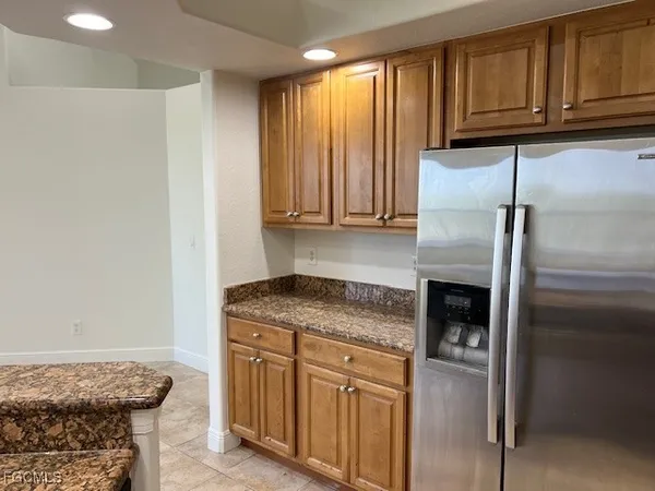 a kitchen with stainless steel appliances granite countertop a refrigerator a stove and a sink with wooden cabinets