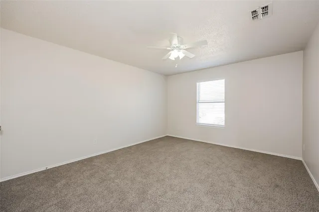 an empty room with a window and a ceiling fan
