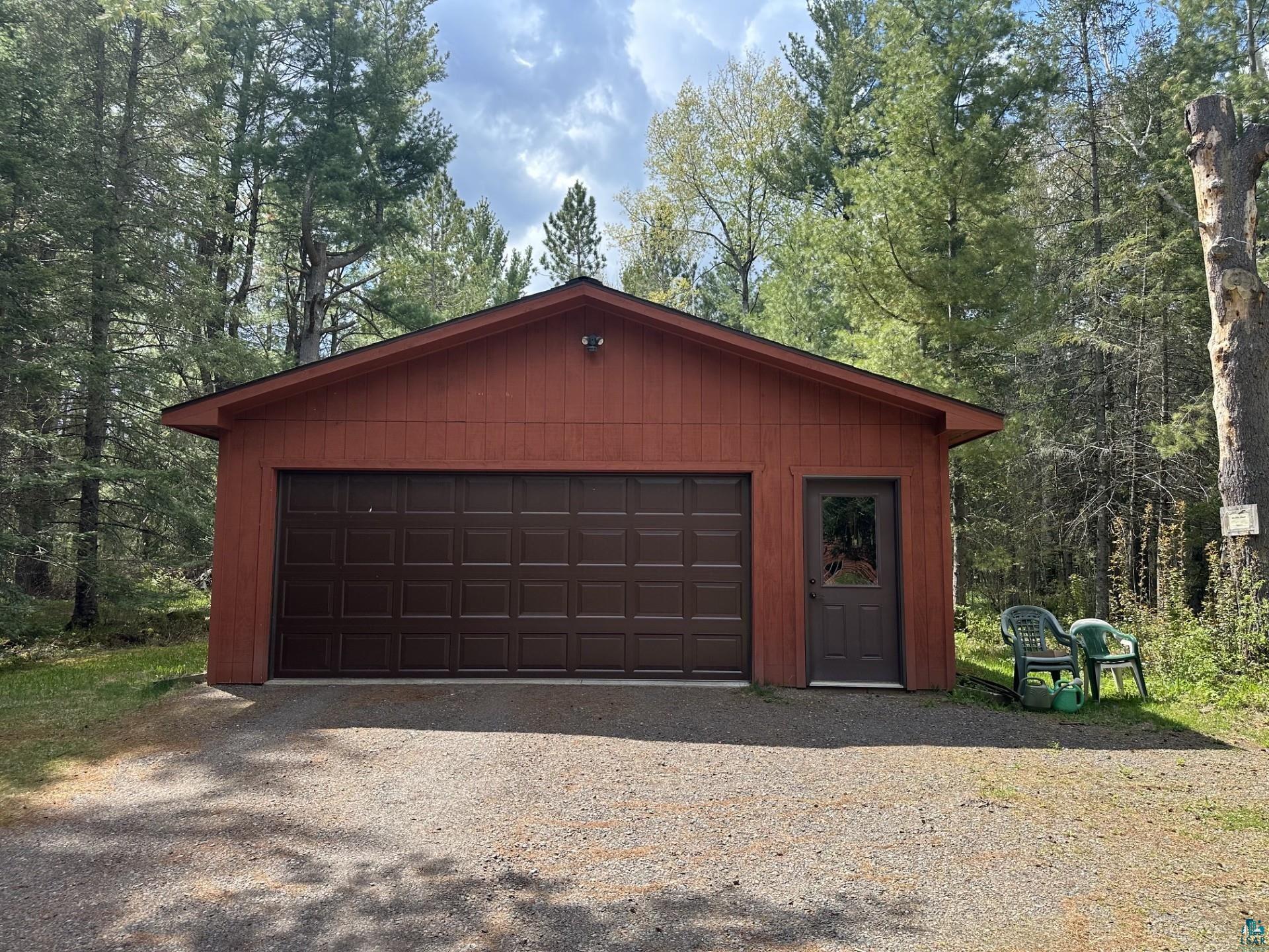 81 Hautaluoma Road Esko, MN 55733 - Photo 43 of 43 Freestanding garage structure featuring a two-car overhead door, a pedestrian entry door with glass insert, and a gable roofline