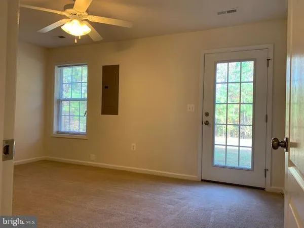 a view of an empty room with window and chandelier fan