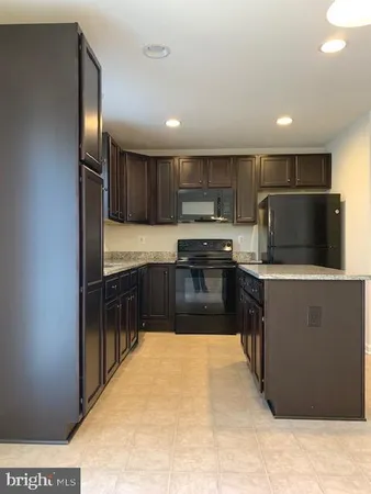 a large kitchen with a large counter top stainless steel appliances and cabinets