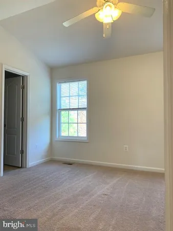 an empty room with a chandelier fan and windows