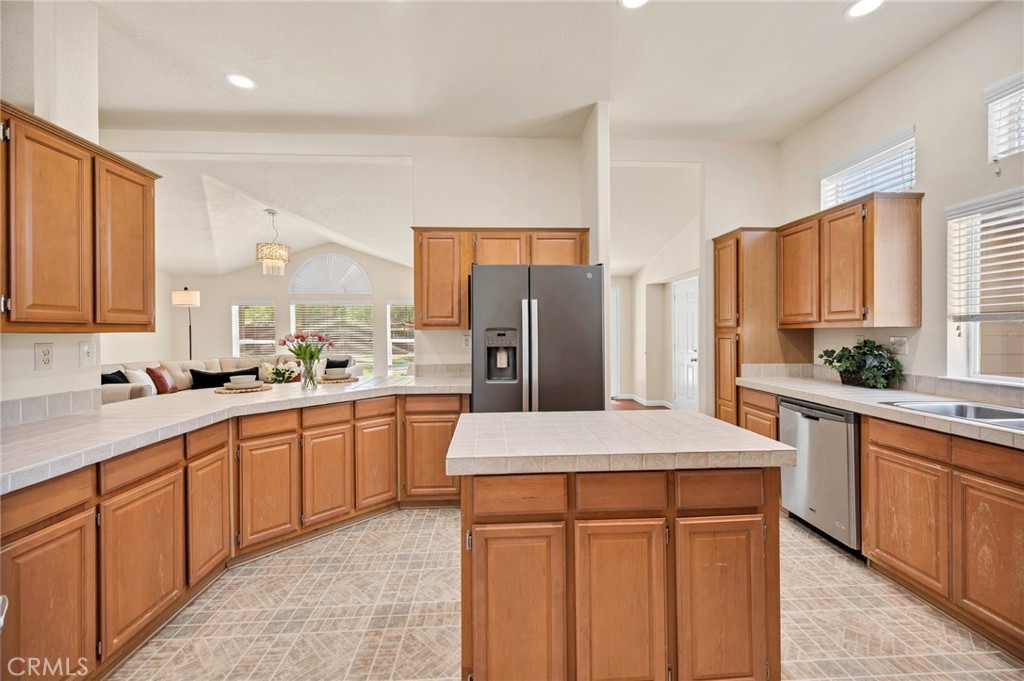 37055 De Portola Road Temecula, CA 92592 - Photo 36 of 67 a kitchen with stainless steel appliances kitchen island granite countertop a refrigerator a sink dishwasher and white cabinets with wooden floor