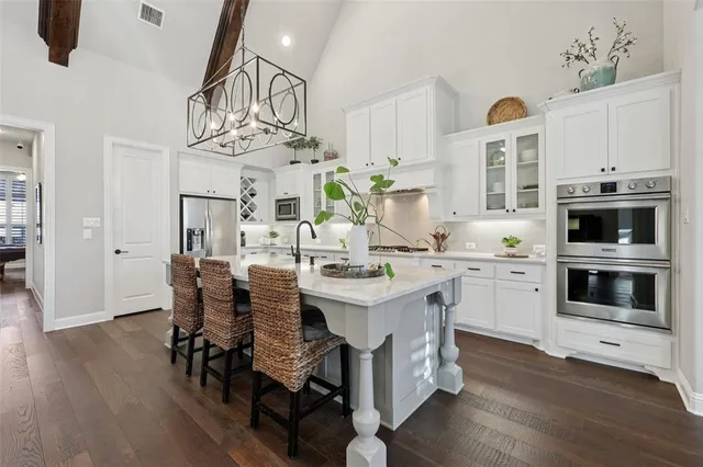 a kitchen with stainless steel appliances a white table chairs and a stove