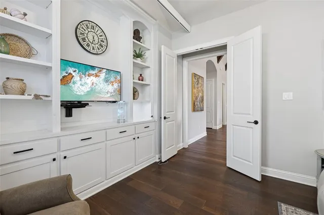 a view of a hallway with painting on the wall and a wooden floor
