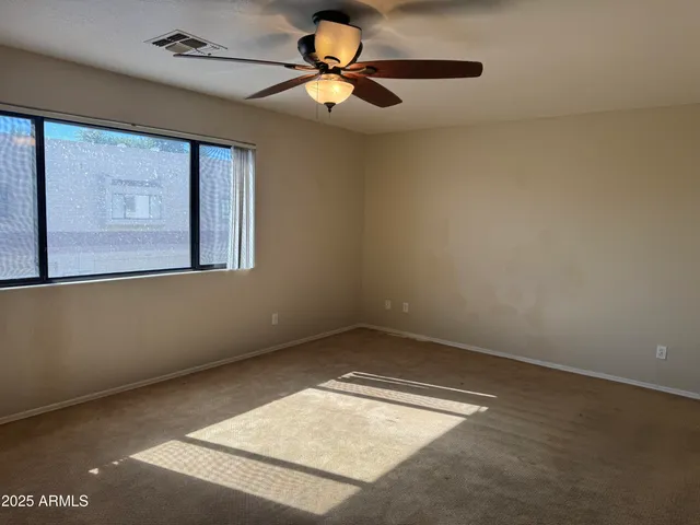 an empty room with windows and fan