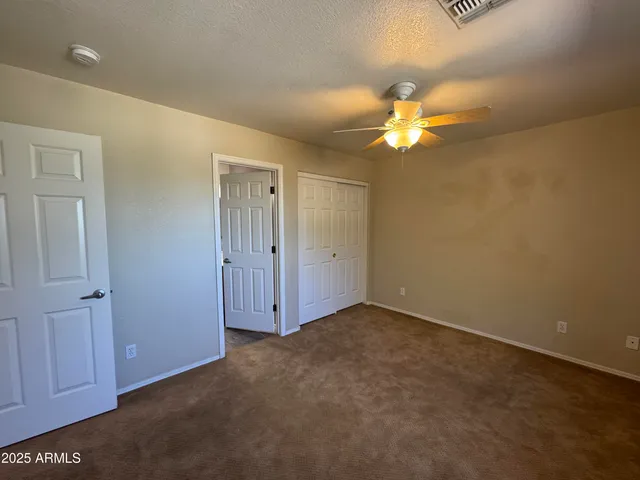 an empty room with closet and a ceiling fan