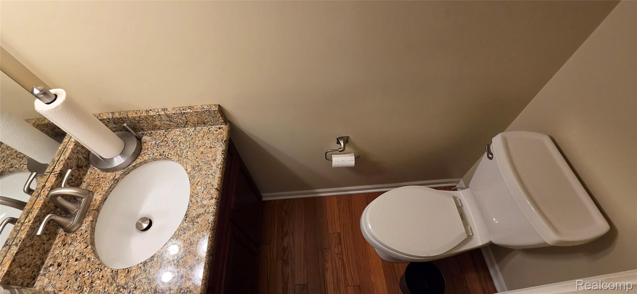 380 Huntington Court Rochester, MI 48307 - Photo 12 of 26 Granite-finish countertop with an undermount sink, wood-finish flooring, and white toilet