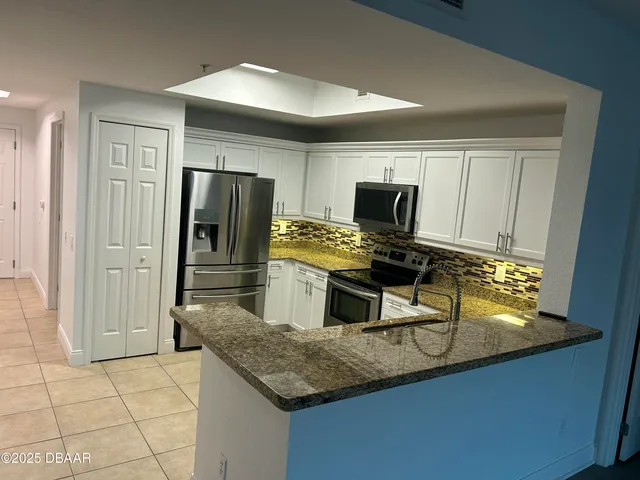 a kitchen with kitchen island granite countertop stainless steel appliances a sink stove refrigerator and cabinets