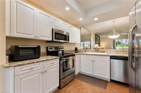 a kitchen with stainless steel appliances granite countertop a sink a stove a refrigerator and a microwave