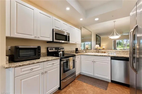 a kitchen with stainless steel appliances granite countertop a sink a stove a refrigerator and a microwave