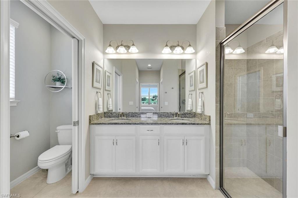 9373 Pocida Court, Unit 104 Naples, FL 34119 - Photo 13 of 24 a bathroom with a granite countertop sink a toilet a mirror and shower
