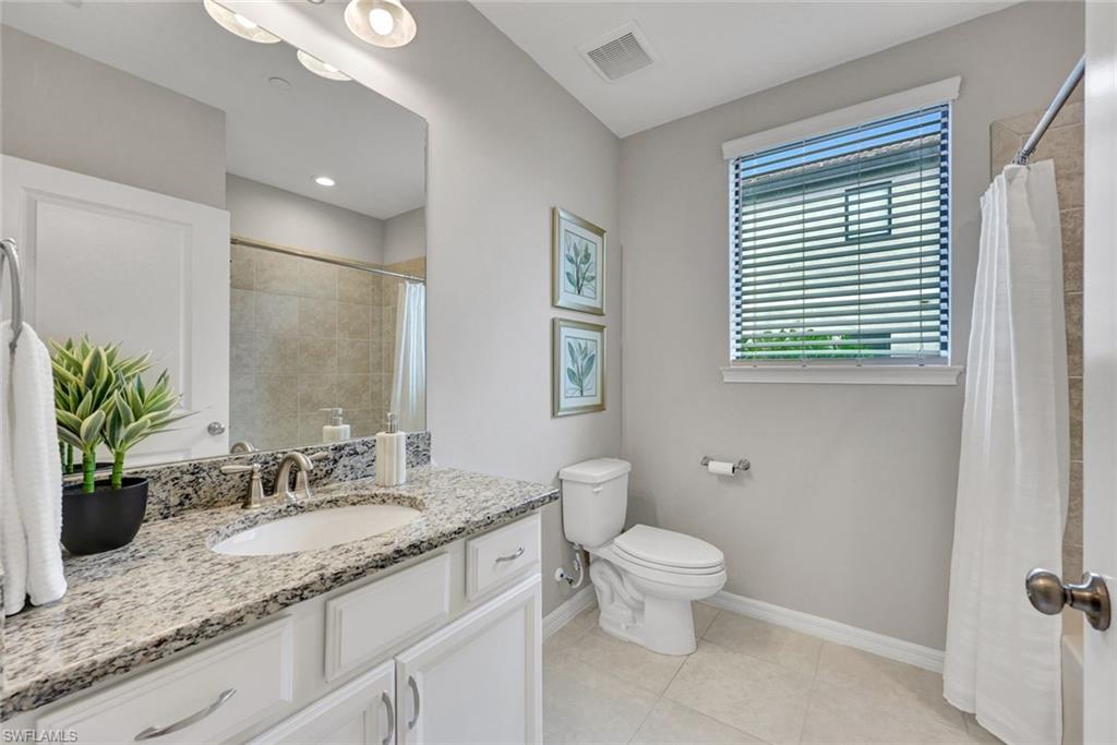 9373 Pocida Court, Unit 104 Naples, FL 34119 - Photo 15 of 24 a bathroom with a granite countertop sink toilet and large mirror