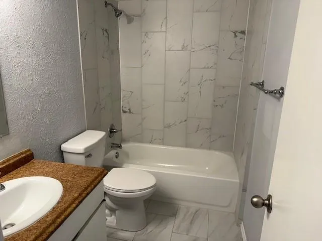 a white toilet and tub sitting next to a bathroom sink