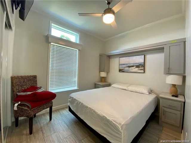 a bedroom with a bed table chair and a window