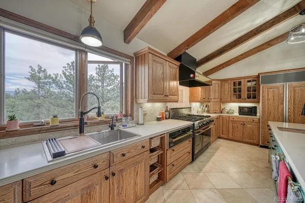 a kitchen with a sink appliances cabinets and a large window