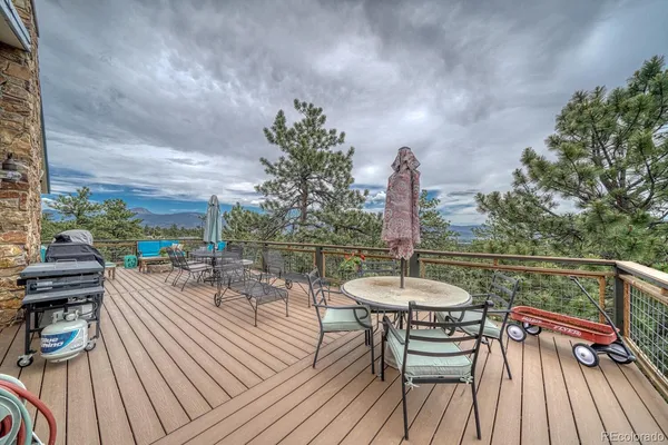 a view of a roof deck with table and chairs a barbeque with wooden floor and fence