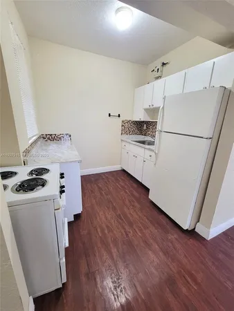 a kitchen with a refrigerator a stove top oven a sink and wooden floor