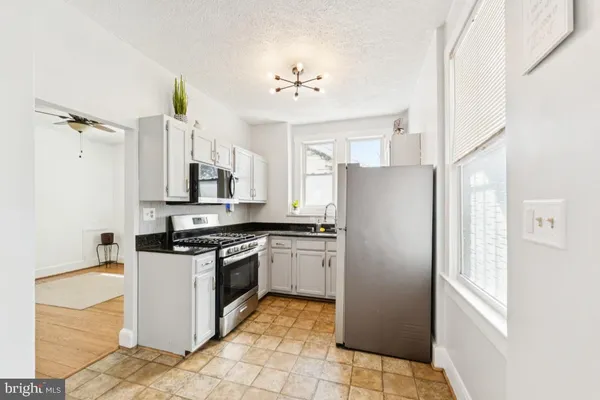 a kitchen with stainless steel appliances granite countertop a refrigerator a stove and a sink