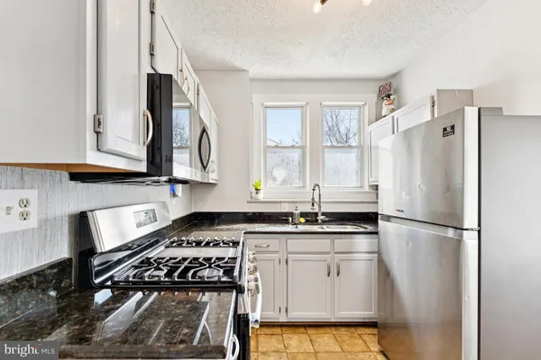 a kitchen with granite countertop a sink stove and refrigerator