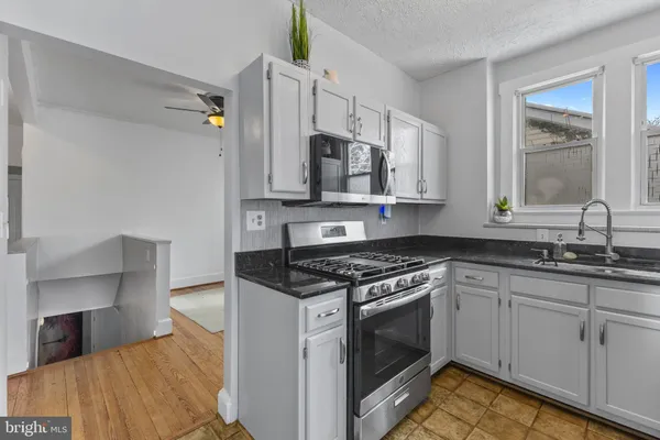 a kitchen with stainless steel appliances granite countertop a stove a sink and a microwave