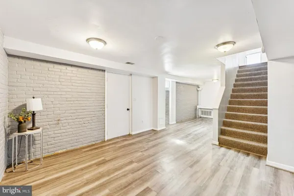 a view of a hallway with wooden floor and a bathroom