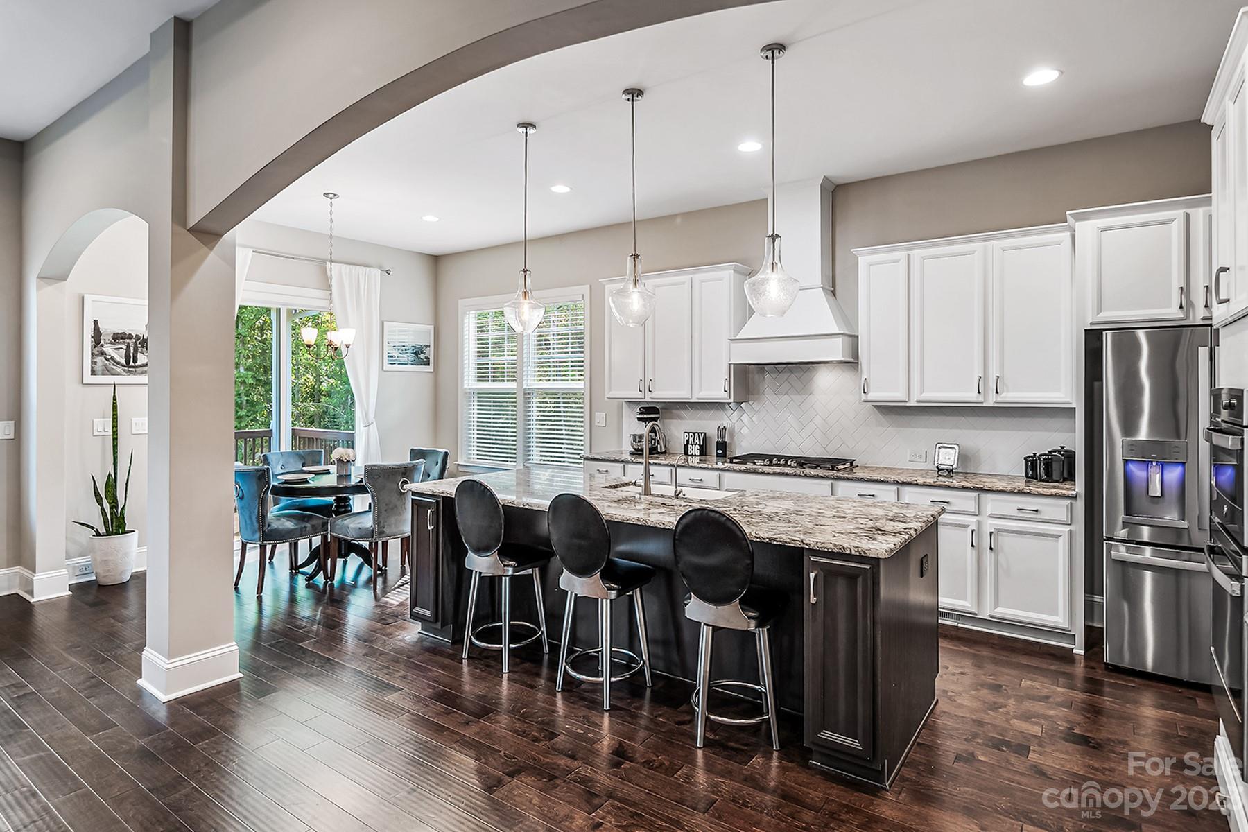 1004 Princessa Drive Wesley Chapel, NC 28104 - Photo 14 of 40 a kitchen with stainless steel appliances granite countertop a table chairs stove and wooden floor