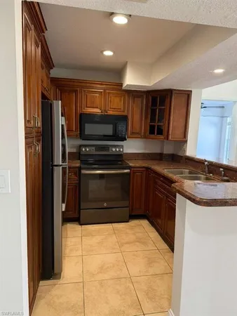 a large kitchen with stainless steel appliances kitchen island granite countertop a refrigerator and a sink
