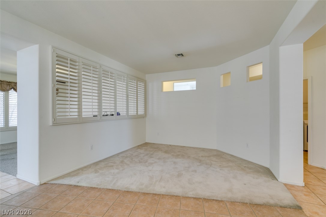 An open living space features plantation shutters, soft carpeting, and durable tile flooring.