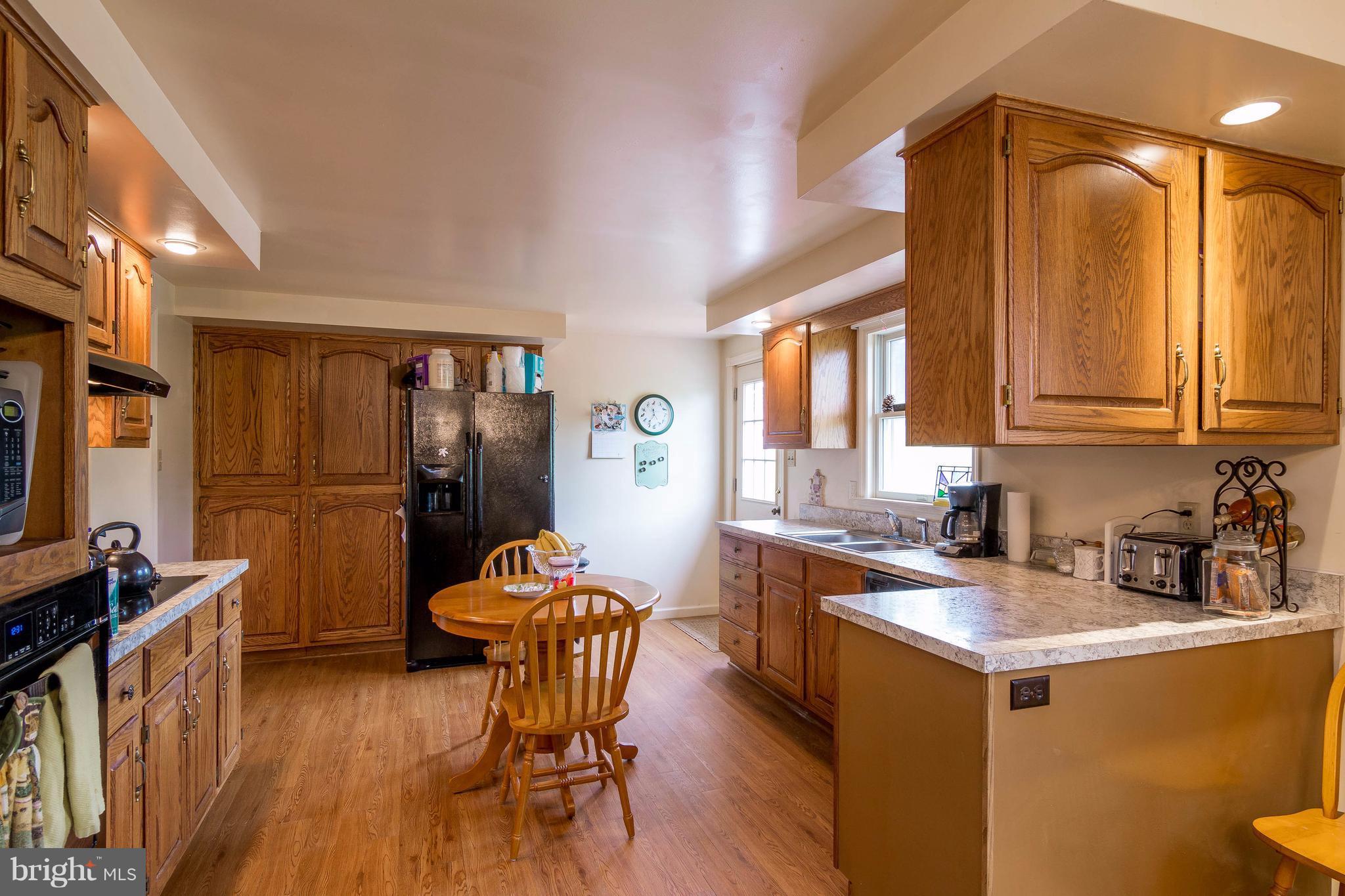 4009 Bill Moxley Road Mount Airy, MD 21771 - Photo 5 of 22 a kitchen with stainless steel appliances granite countertop a refrigerator a sink dishwasher a stove and a dining table with wooden floor