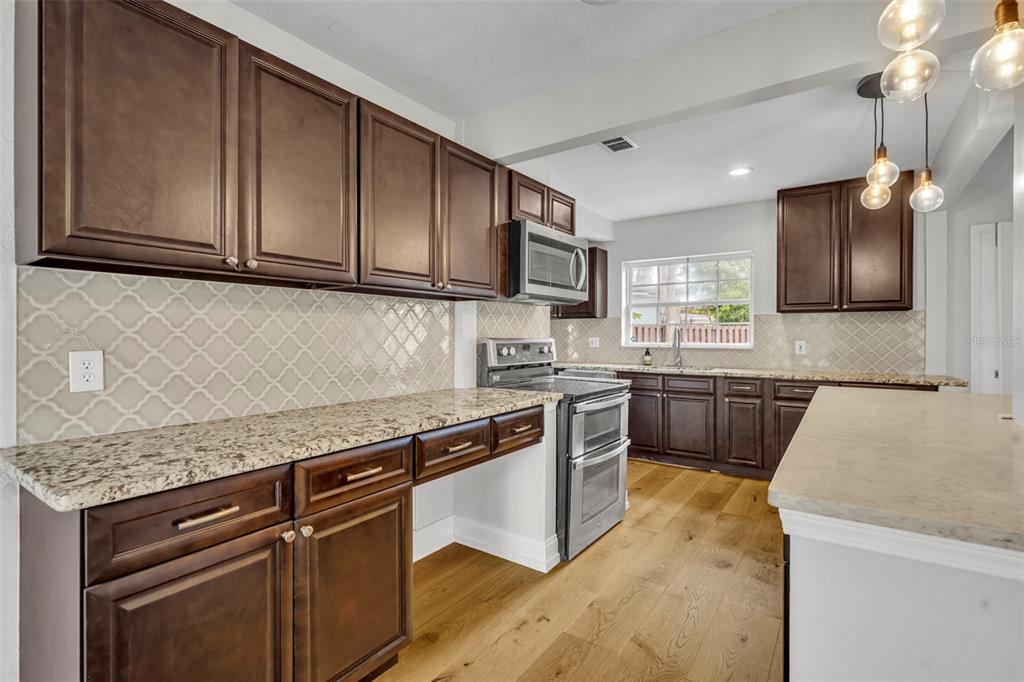 4234 Kendrick Road Orlando, FL 32804 - Photo 13 of 46 a kitchen with stainless steel appliances granite countertop wooden cabinets a stove top oven a sink and dishwasher