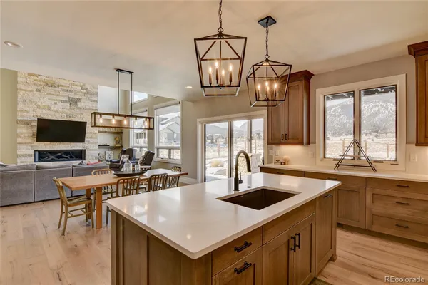 a kitchen with a stove a sink dishwasher a dining table and chairs with wooden floor