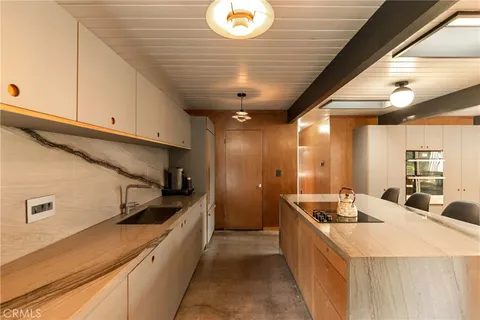 a large kitchen with kitchen island a sink stainless steel appliances wooden floor and cabinets