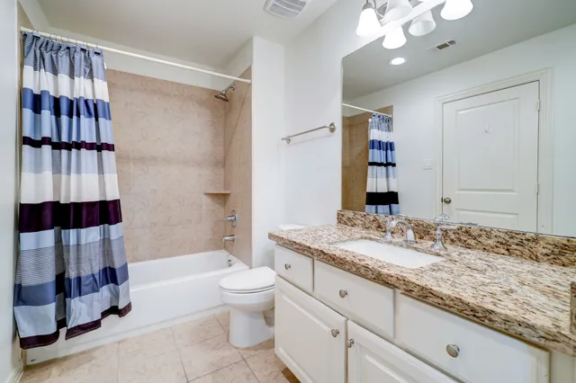 a bathroom with a granite countertop sink a toilet and shower