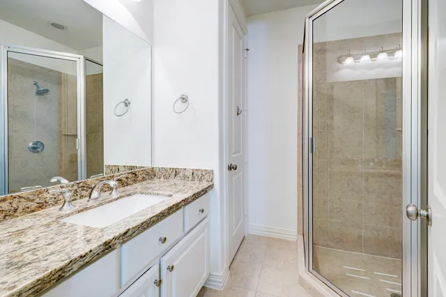 a bathroom with a granite countertop sink a mirror and a shower