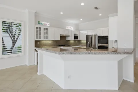 a kitchen with kitchen island granite countertop a sink counter top space appliances and cabinets