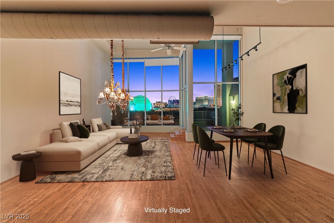 Virtually staged |Living area with a ceiling fan, a view of city, wood finished floors, a chandelier, and expansive windows