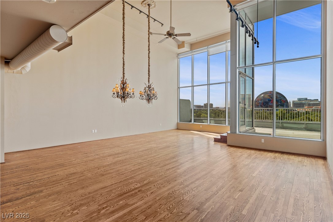 360 East Desert Inn Road, Unit 605 Las Vegas, NV 89109 - Photo 13 of 43 Unfurnished living room with wood finished floors, ceiling fan, a high ceiling, and a chandelier